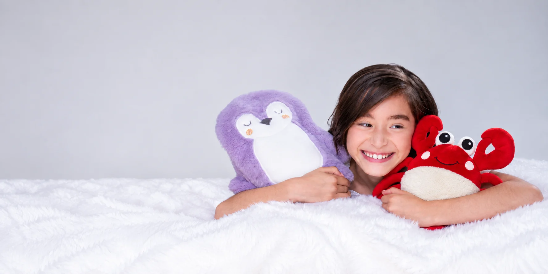Niña sonriendo mientras abraza al pingüino morado y a Krapi, el cangrejo APAPACHO